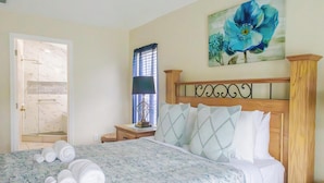 A bedroom with a bed, a nightstand, a lamp, and a painting on the wall.