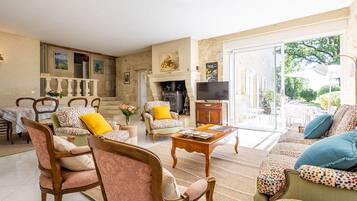 A spacious living room with a fireplace, comfortable seating, and a large window offering a view of the outdoors.