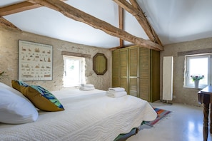 Un dormitorio con una cama grande, vigas de madera, una ventana con vistas, un mapa enmarcado en la pared y un armario verde.