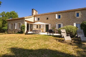 A stone house with a patio, outdoor seating, and a barbecue area.