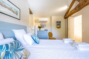 A hotel room with a bed, a dresser, a chair, and a framed picture on the wall. - Stone Cabin with Swimming Pool - King-Size Beds & Views of the Pyrenees (Gondrin)