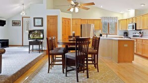 A spacious kitchen with wooden cabinets, a central island, and a dining area with chairs.