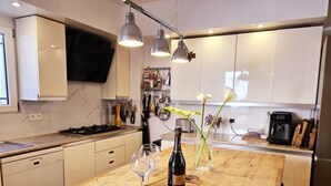 Una cocina moderna con una isla de madera, copas de vino, una botella de champán y un jarrón con flores.