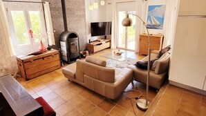 Una sala de estar moderna con chimenea, sofá, televisor y un cuadro de un velero.