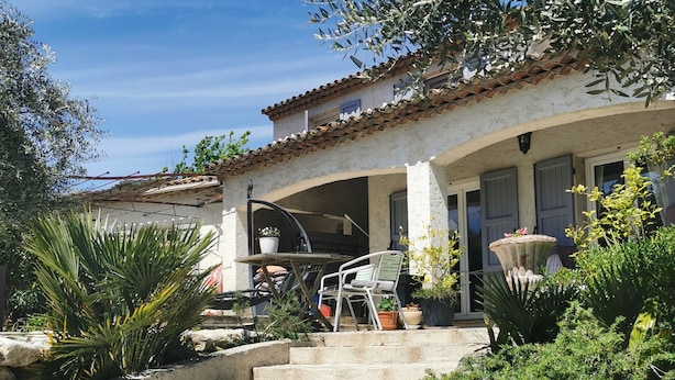 Una escalera de piedra que conduce a un espacio al aire libre cubierto, con una mesa y sillas de patio.