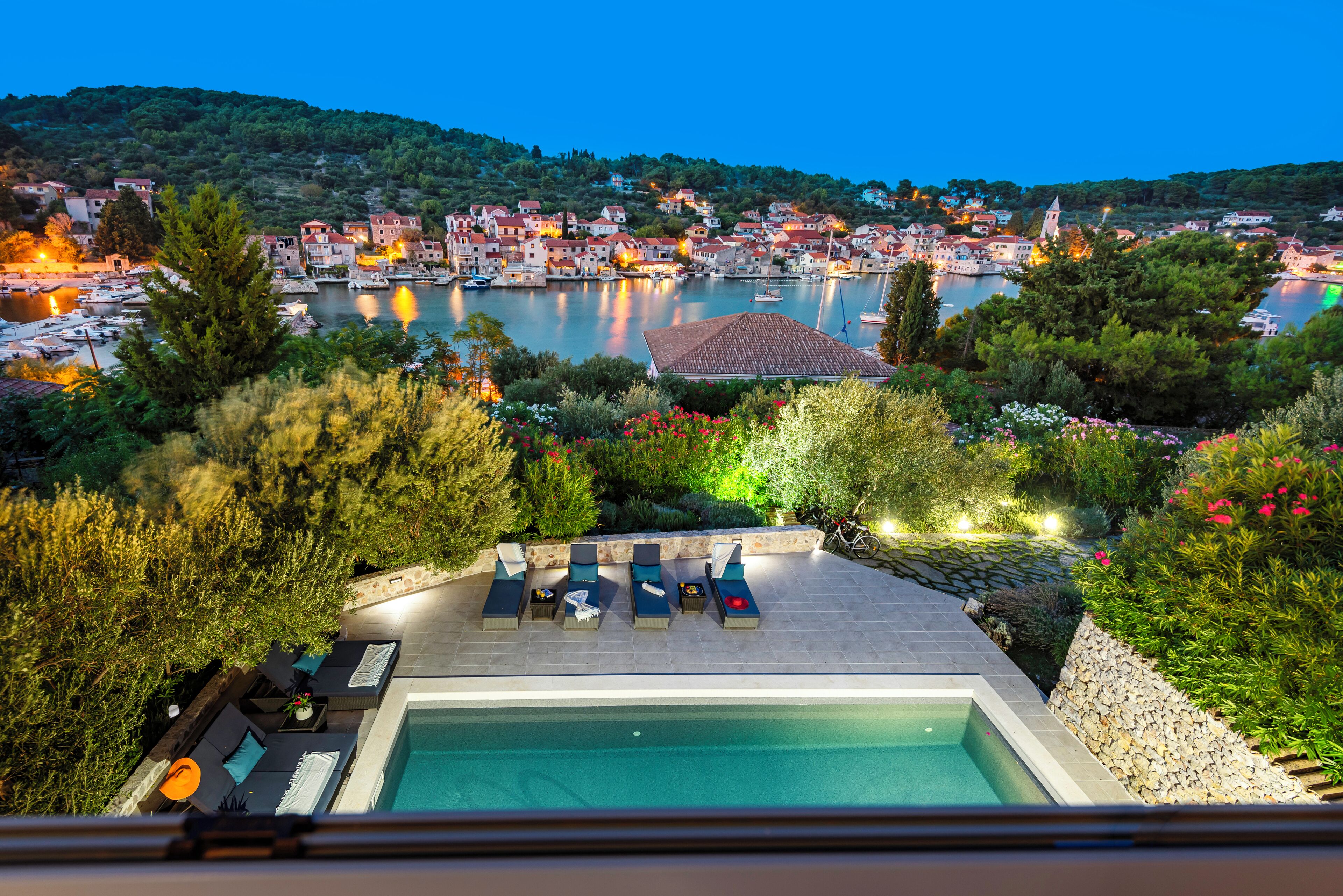 Ein Poolbereich mit Liegestühlen und Blick auf eine Stadt am Wasser.
