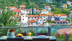 A coastal town with stone buildings, a waterfront, and a dining area with outdoor seating. - Private stone villa on the island for 10 people with pool and sea view (Prvic Luka)