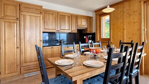 Een houten keuken met een eettafel voor zes personen, compleet met stoelen en een centraal kookeiland.