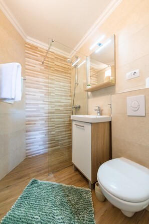 Un baño moderno con cabina de ducha de vidrio, un lavabo e inodoro.