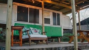A campervan parked under a wooden structure with a bench and hanging lanterns. - Lost Hill Lake Charming Camper (Central Township)