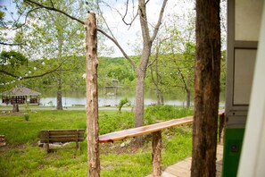 Un banc en bois et un kiosque situés près d’un lac, entourés d’arbres et de verdure.