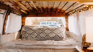 Un ambiente acogedor con cama, techo de madera y luces de tipo guirnalda.