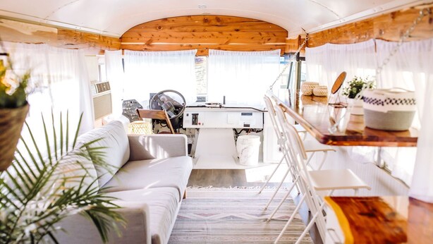Een gezellig interieur van een camper, met een bank, eettafel en keuken.