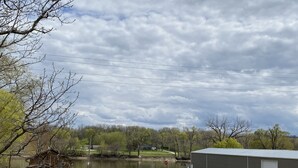 A grassy area with a building, a pond, and trees. - "THE SHOP" retro 60's (Keosauqua)