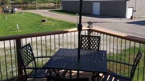 A deck with a table and chairs, an umbrella, and a building in the background. - "THE SHOP" retro 60's (Keosauqua)