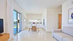 A modern living room with a sofa, a TV on a wooden stand, and a dining area with a table and chairs. - VILLA DARDA (Alcamo)