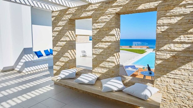 A modern room with stone walls, a pool view, and a seating area with cushions. - VILLA DARDA (Alcamo)