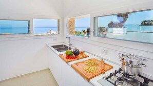A modern kitchen with large windows overlooking a coastal view, a sink, and a stove. - VILLA DARDA (Alcamo)
