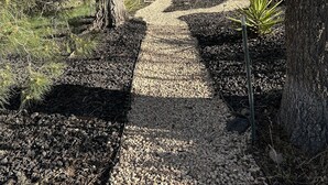 Un chemin de gravier bordé d’arbres et d’arbustes, qui mène à un véhicule situé au loin.