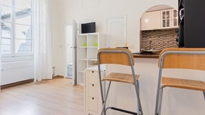 A modern kitchen with white cabinetry, a TV on a shelf, and two chairs. - GuestHost - Modern and cozy 25 sqm studio apartment, ideal for two people, located on the 2nd floor of a characteristic period building without lift. The property is located within the Traffic-Restricted Area of the historic center and is the ideal solut (Firenze)