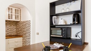 A kitchen with a microwave, coffee maker, and a shelf with wine glasses. - GuestHost - Modern and cozy 25 sqm studio apartment, ideal for two people, located on the 2nd floor of a characteristic period building without lift. The property is located within the Traffic-Restricted Area of the historic center and is the ideal solut (Firenze)