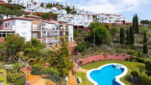 A hillside residential area with white buildings, a swimming pool, and lush greenery. - Apartamento Ladera by Solset (Málaga)