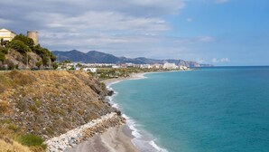 A coastal town with a beach, a historic tower, and a mountain range in the background. - Apartamento Ladera by Solset (Málaga)
