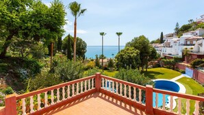 A balcony with a view of a swimming pool, lush greenery, and a coastal landscape. - Apartamento Ladera by Solset (Málaga)