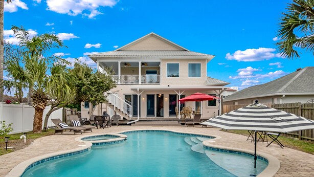 Une maison à deux étages avec une piscine, un patio couvert et un parasol rouge.