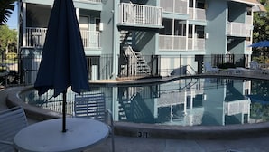 Un immeuble à plusieurs étages doté de balcons, d’une piscine et d’un espace extérieur aménagé pour s’asseoir.