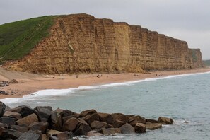 Une falaise côtière avec une plage et un premier plan rocheux.