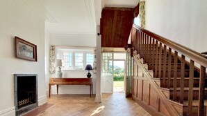 Amplia habitación con escalera de madera, chimenea y ventana con vistas al exterior.