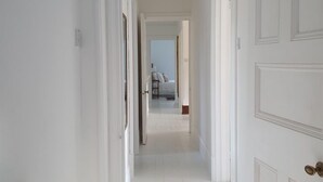 Un pasillo con paredes blancas y puertas que dan a un dormitorio.