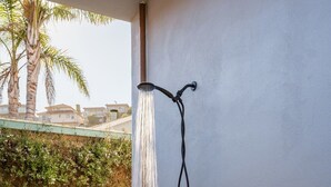 A wall-mounted shower with a hose, a wooden deck, and a gravel area. - Amazing Beach House w/ Jacuzzi and Fire Pit (Aptos)
