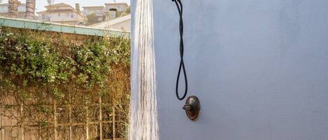 Una ducha empotrada con manguera, una terraza de madera y una zona con grava.