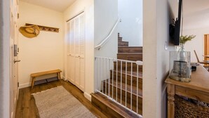 Ein Korridor mit einer hölzernen Sitzbank, einer weißen Tür und einer Treppe mit weißer Geländer.