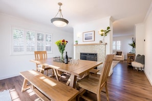 A spacious dining area with a wooden table and benches, a fireplace, and a view of the living room. - Amazing Beach House w/ Jacuzzi and Fire Pit (Aptos)