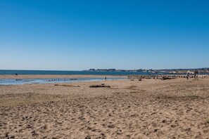 Una playa con muelle, cielo despejado y mar tranquilo.