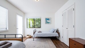 A bedroom with a bed, a bedside table, a wardrobe, and a window with a view of trees.