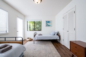 A bedroom with a bed, a bedside table, a wardrobe, and a window with blinds. - Amazing Beach House w/ Jacuzzi and Fire Pit (Aptos)