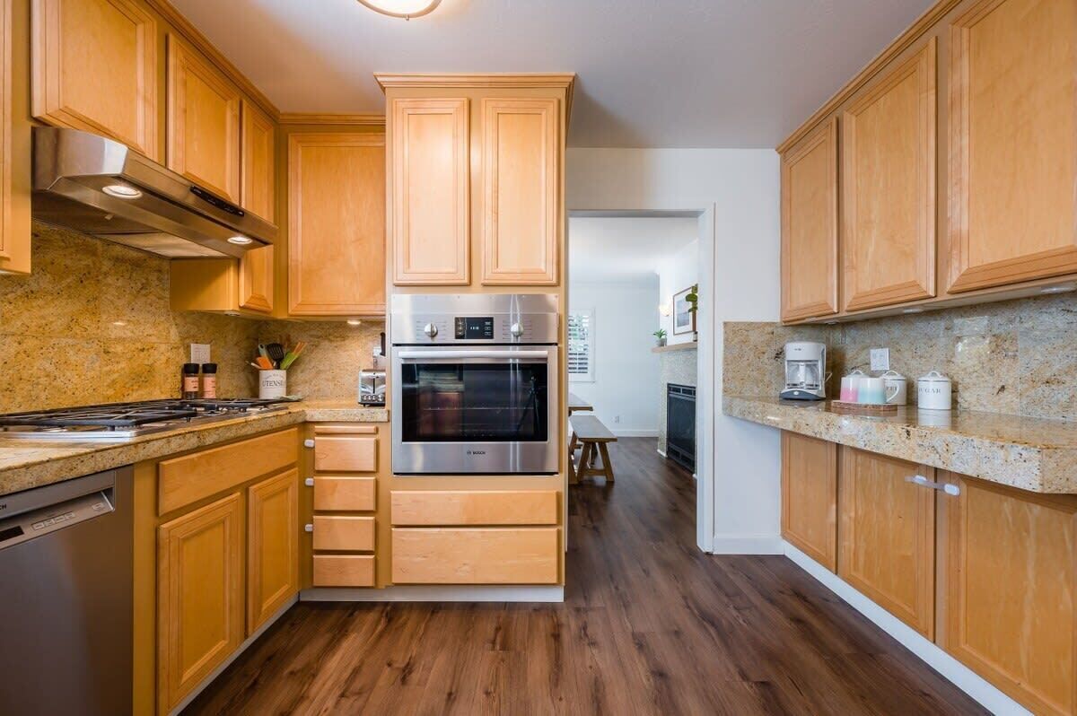Una cocina con gabinetes de madera, electrodomésticos de acero inoxidable y encimeras de granito.