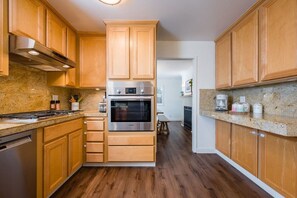 Una cocina con gabinetes de madera, electrodomésticos de acero inoxidable y encimeras de granito.