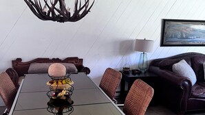 A conference room with a glass table, brown woven chairs, a dark wooden sideboard, and a mounted painting on the wall. - Welcoming & Comfortable Townhome Great Multi-Level Layout (Eagle Vail)