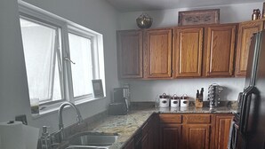 A kitchen with granite countertops, wooden cabinets, a stainless steel refrigerator, and a window providing natural light. - Welcoming & Comfortable Townhome Great Multi-Level Layout (Eagle Vail)
