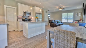 A modern kitchen with white cabinetry, a central island, stainless steel appliances, and pendant lighting.