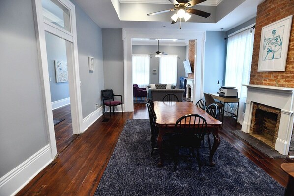 A dining area with a wooden table and chairs, a ceiling fan, and a fireplace.