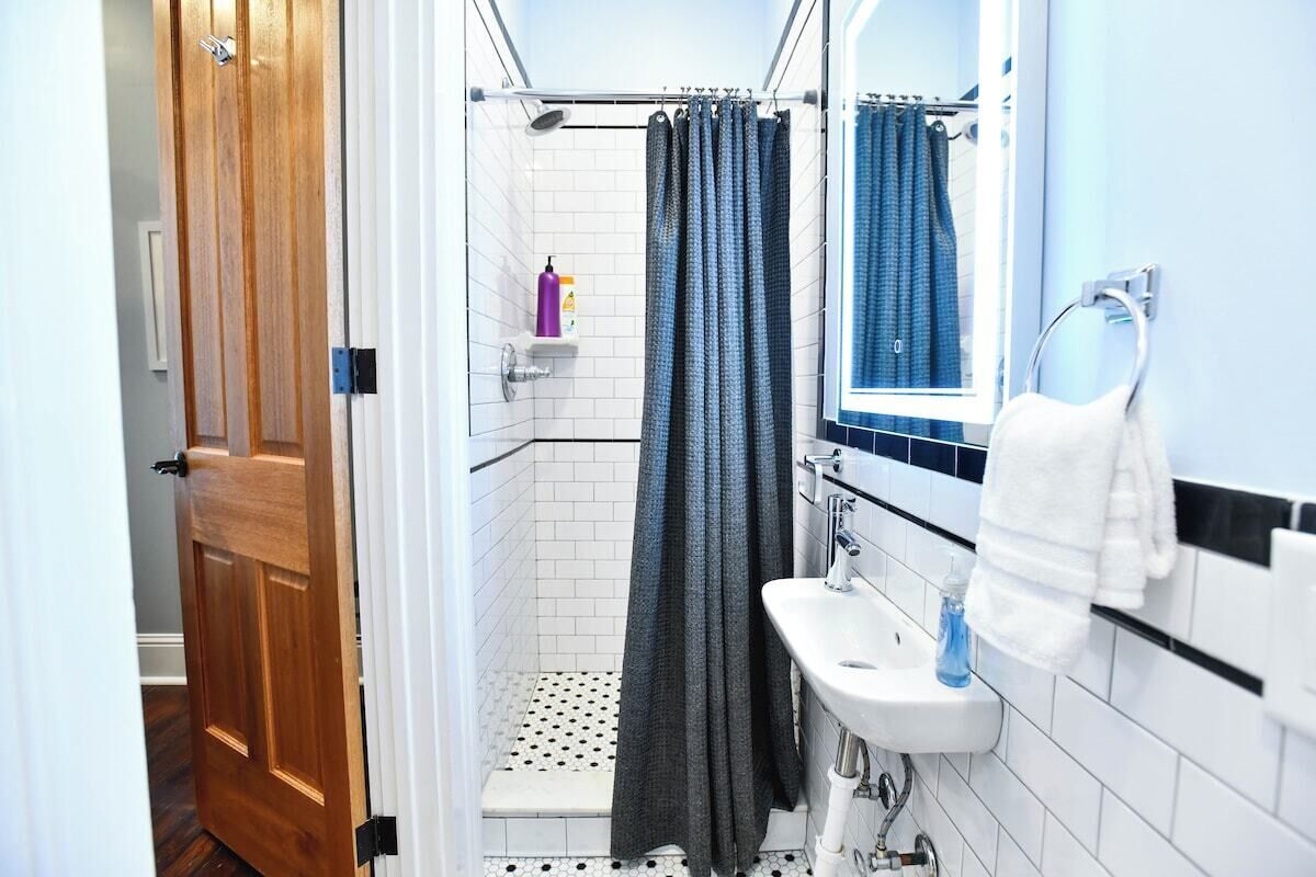 A bathroom with a shower, a sink, and a towel rack.