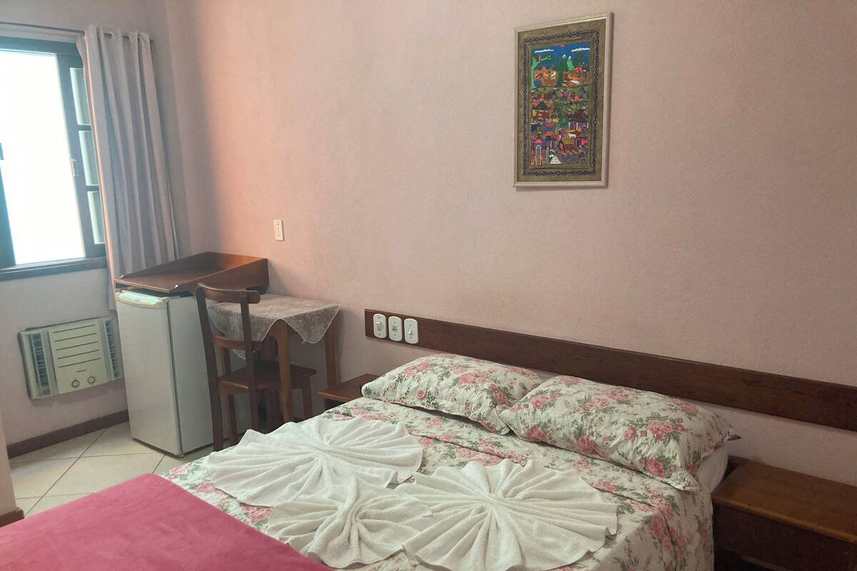 A hotel room with a bed, a desk, and a chair.