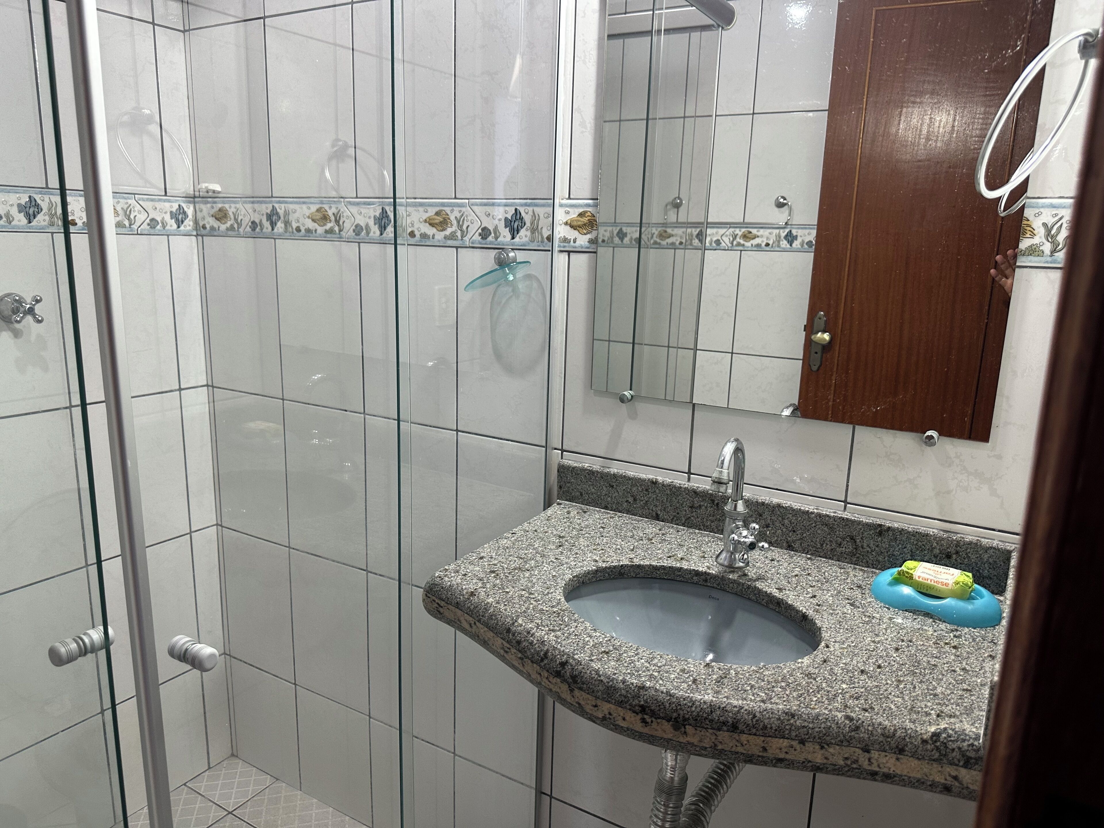 Un baño con cabina de ducha de vidrio, lavamanos de granito y puerta de madera.