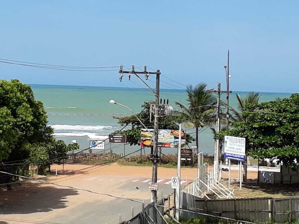 Uma estrada costeira com vista para o oceano, linhas de energia e várias placas.